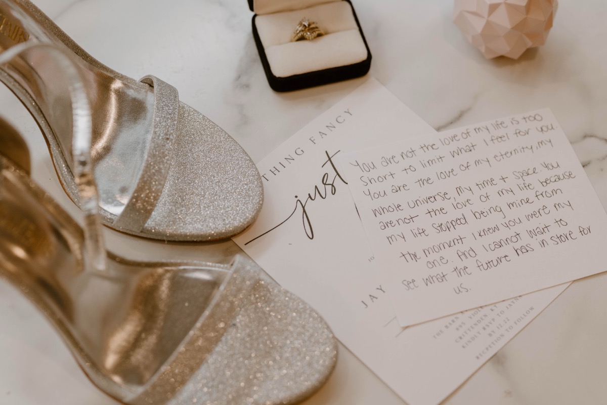 Handwritten wedding vows with ring box and gold heels
