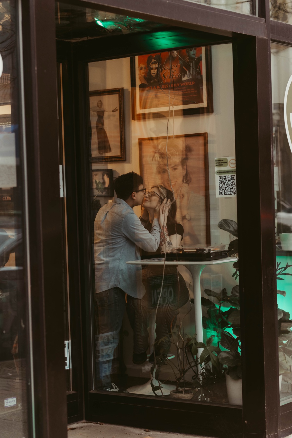 Couple sharing an intimate moment through a record store window